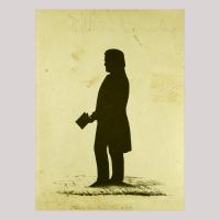 Silhouette of a man with a book in his hand facing left, inkling of ground 