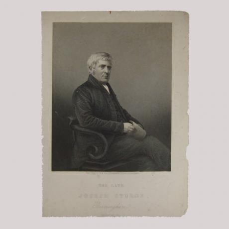 Silhouette of a man with a piece paper in his hand sitting on a stool, facing right